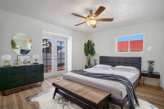 bedroom with light wood-type flooring, access to outside, french doors, and a textured ceiling