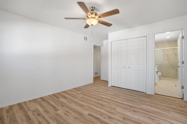 unfurnished bedroom featuring light wood-style floors, a textured ceiling, visible vents, and a closet