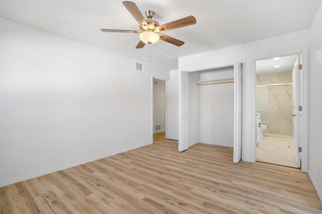 unfurnished bedroom featuring a textured ceiling, light wood-type flooring, ensuite bath, and visible vents