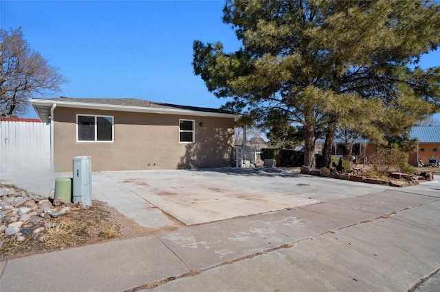 view of side of home with fence and stucco siding