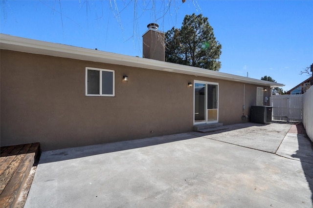 rear view of property featuring entry steps, central AC unit, fence, a patio area, and stucco siding