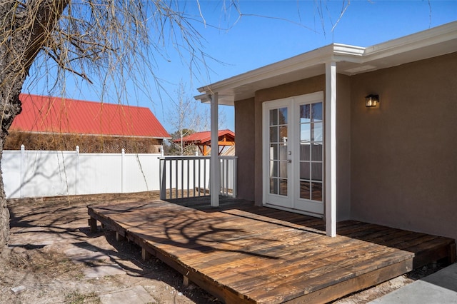 wooden terrace with french doors and a fenced backyard