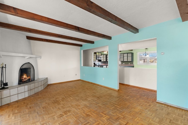 unfurnished living room featuring beam ceiling, a textured ceiling, baseboards, and a tiled fireplace