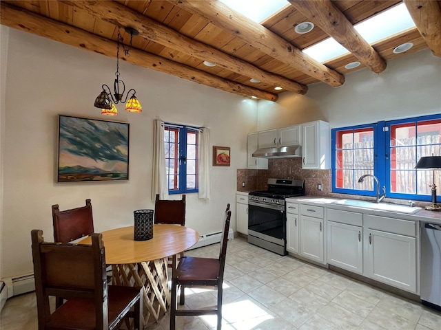 kitchen with decorative light fixtures, light countertops, appliances with stainless steel finishes, white cabinets, and under cabinet range hood