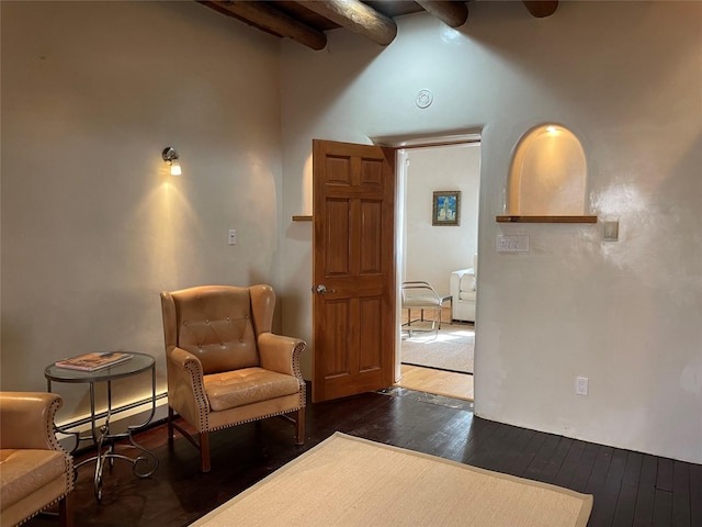 sitting room featuring dark wood-type flooring, baseboard heating, and beam ceiling