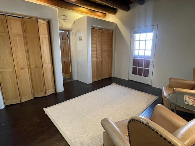 interior space with dark wood-style flooring and beamed ceiling