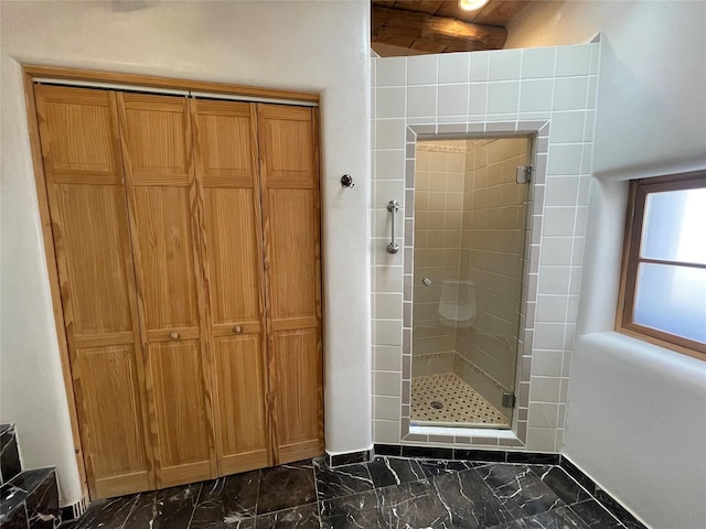 bathroom featuring marble finish floor, a shower stall, and a closet