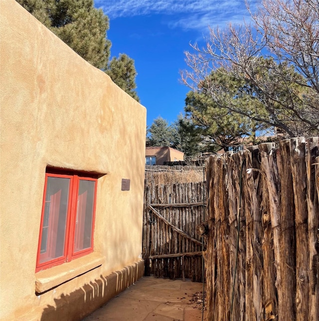 view of side of home featuring fence and stucco siding