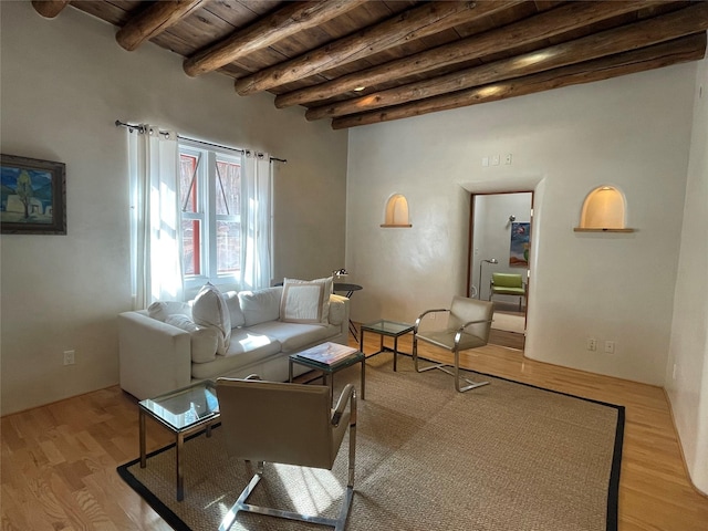 living room with beam ceiling, light wood-style flooring, and wood ceiling