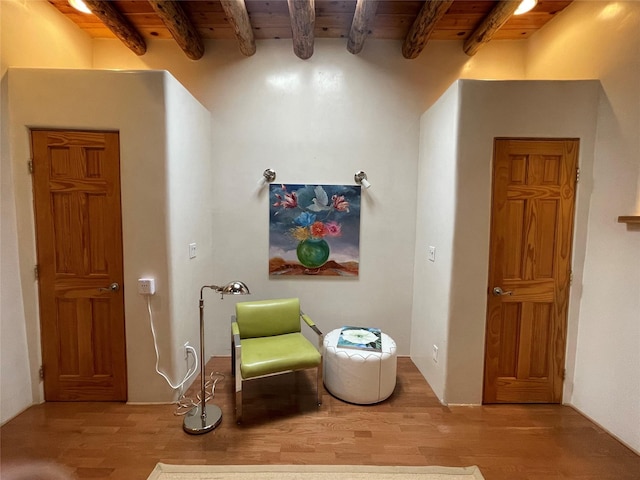 living area with light wood-style floors, wood ceiling, and beam ceiling