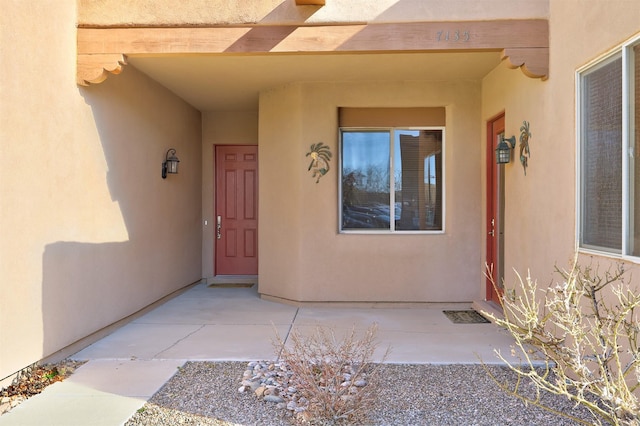 view of exterior entry featuring a patio area and stucco siding