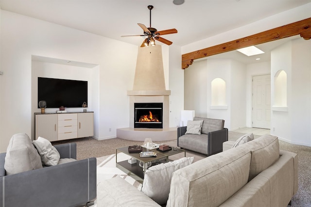 living area with beam ceiling, light carpet, a fireplace, and baseboards