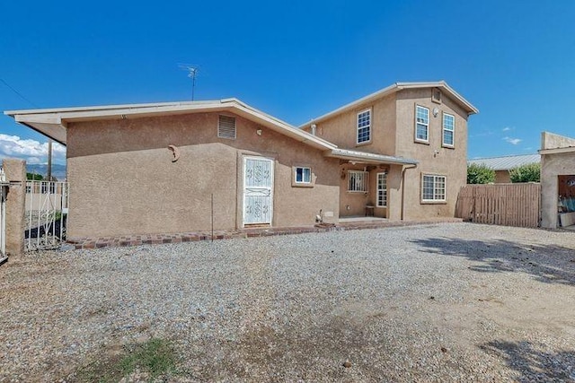 rear view of house featuring fence and stucco siding