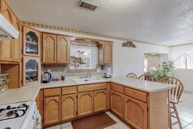 kitchen with a breakfast bar area, light countertops, a sink, white range with gas cooktop, and a peninsula