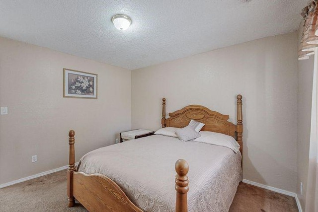 bedroom with light carpet, a textured ceiling, and baseboards