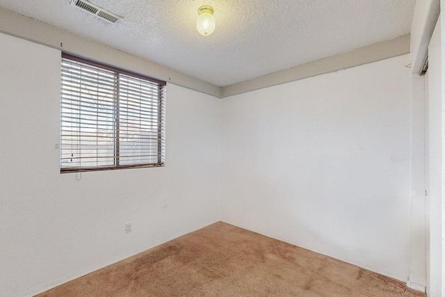 unfurnished room featuring carpet floors, visible vents, and a textured ceiling