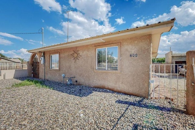 rear view of house featuring fence and stucco siding