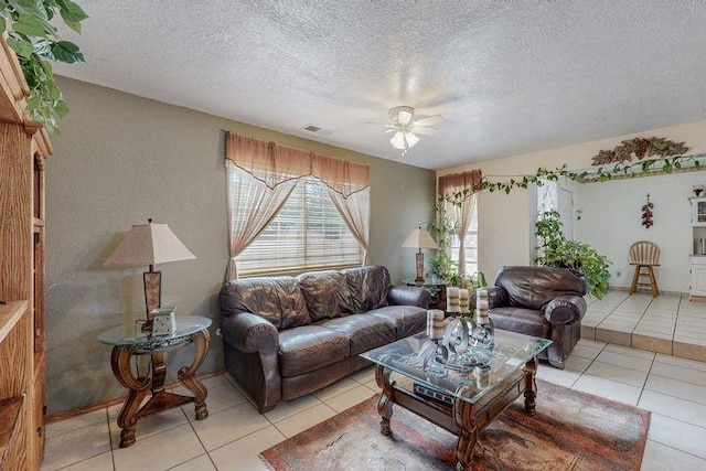 living room with light tile patterned floors, a textured ceiling, visible vents, and a ceiling fan