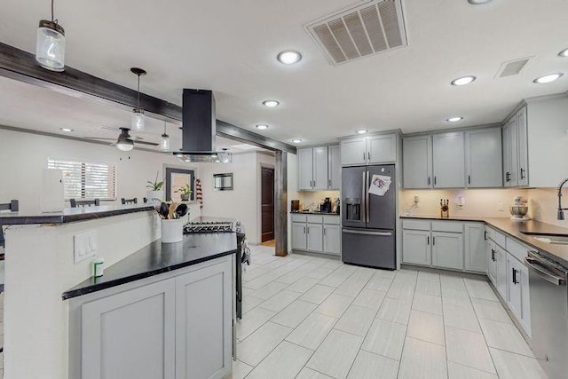 kitchen with appliances with stainless steel finishes, dark countertops, visible vents, and island range hood