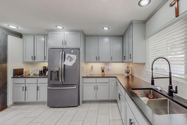 kitchen featuring dark countertops, a sink, stainless steel refrigerator with ice dispenser, and recessed lighting