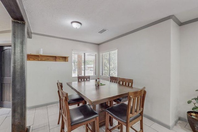 dining space featuring light tile patterned flooring, crown molding, visible vents, and baseboards