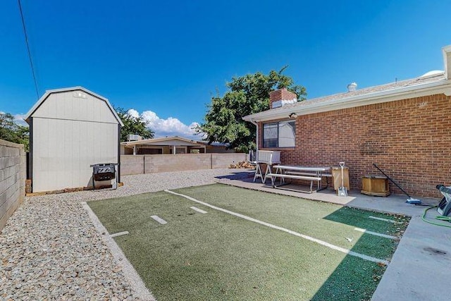 view of yard with a shed, a patio area, a fenced backyard, and an outdoor structure