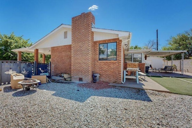 back of property with a patio area, brick siding, fence, and a fire pit