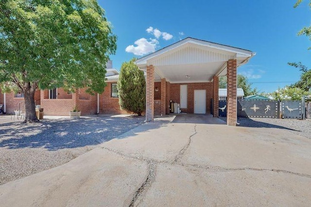 ranch-style house with a carport, fence, concrete driveway, and brick siding