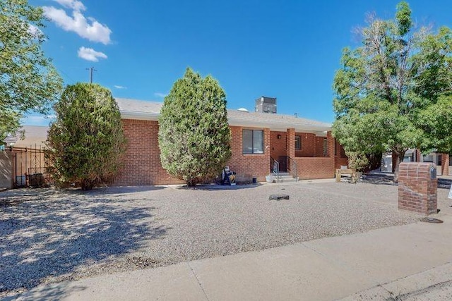 ranch-style home featuring fence and brick siding