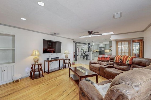 living area featuring visible vents, a ceiling fan, ornamental molding, light wood-type flooring, and recessed lighting