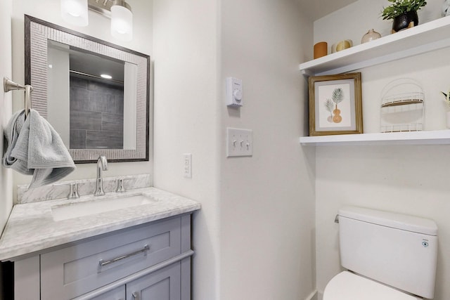 bathroom featuring toilet, a shower, and vanity