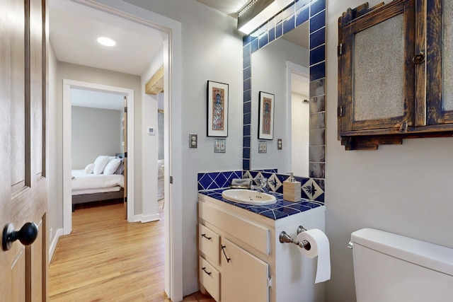 bathroom featuring connected bathroom, toilet, wood finished floors, vanity, and baseboards