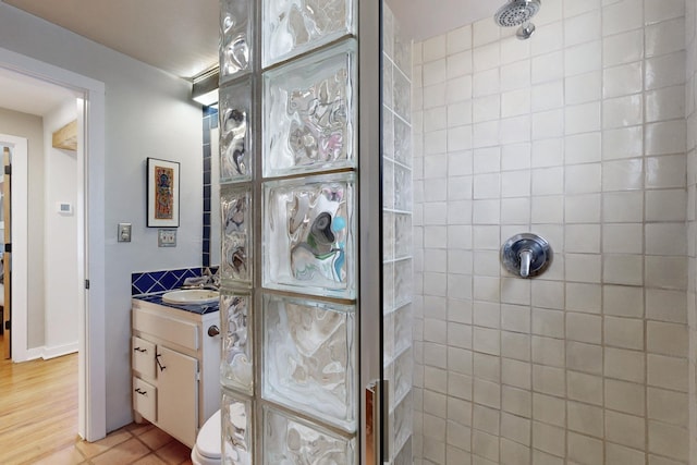 bathroom with toilet, tiled shower, and vanity