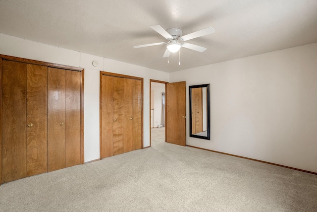 unfurnished bedroom with multiple closets, ceiling fan, and carpet floors