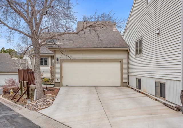 exterior space with a garage, concrete driveway, and a shingled roof