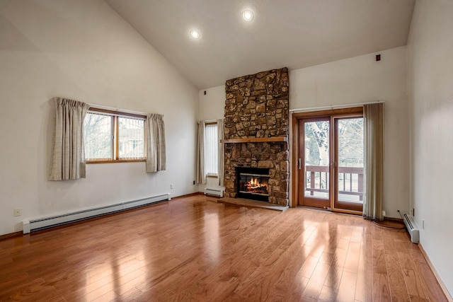 unfurnished living room with a baseboard heating unit, a fireplace, high vaulted ceiling, and wood finished floors