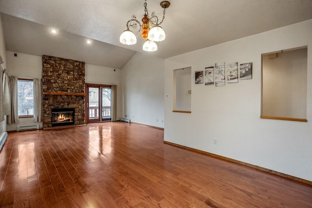 unfurnished living room with a baseboard heating unit, a wealth of natural light, a stone fireplace, and wood finished floors