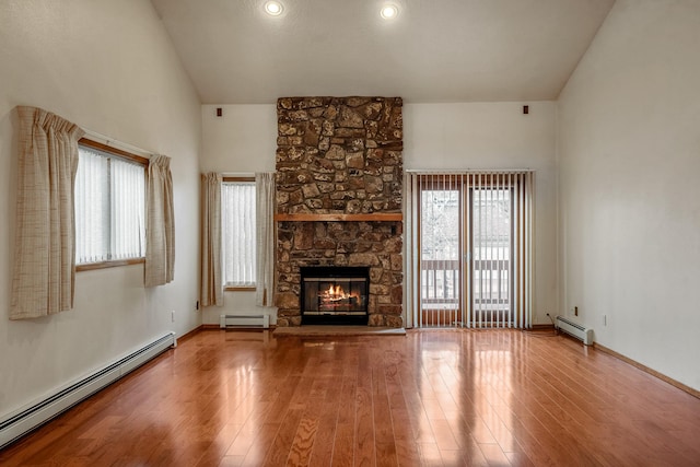 unfurnished living room featuring plenty of natural light, baseboard heating, and wood finished floors