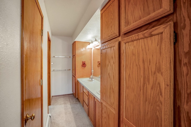 full bathroom with double vanity, a baseboard radiator, a sink, carpet, and a closet