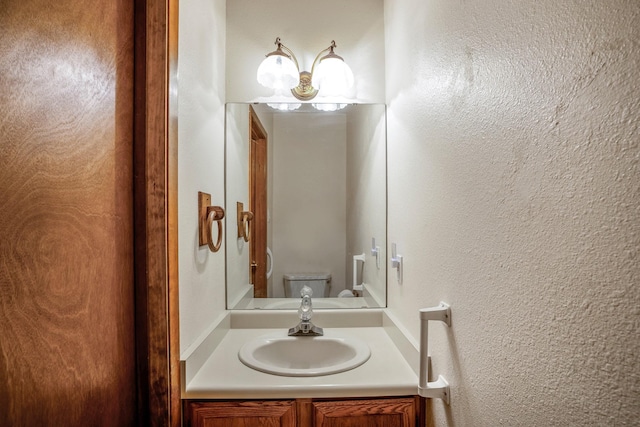 half bathroom with a textured wall, vanity, and toilet