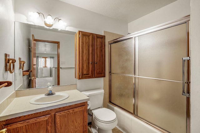 bathroom featuring enclosed tub / shower combo, vanity, and toilet