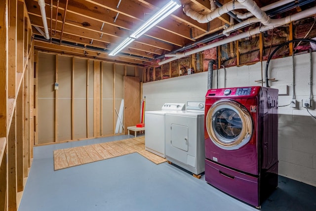 laundry room featuring laundry area, concrete block wall, and washer and dryer