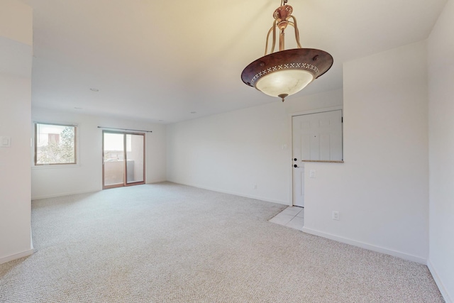 unfurnished room with light colored carpet and baseboards