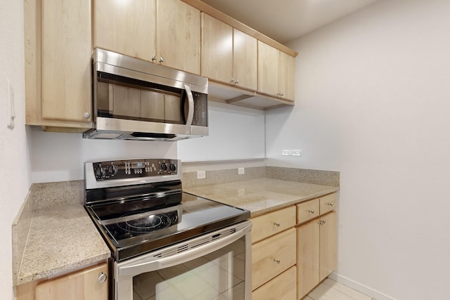 kitchen with baseboards, appliances with stainless steel finishes, light countertops, and light brown cabinetry