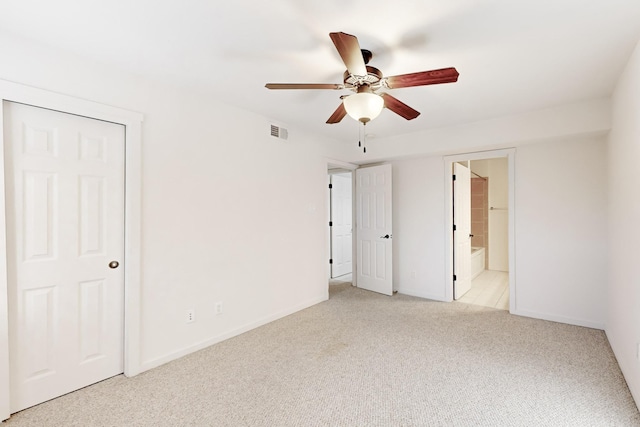 unfurnished bedroom featuring light carpet, a ceiling fan, visible vents, baseboards, and ensuite bath