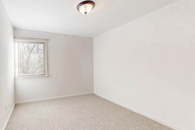 spare room featuring baseboards and light colored carpet