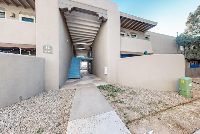 entrance to property featuring fence and stucco siding