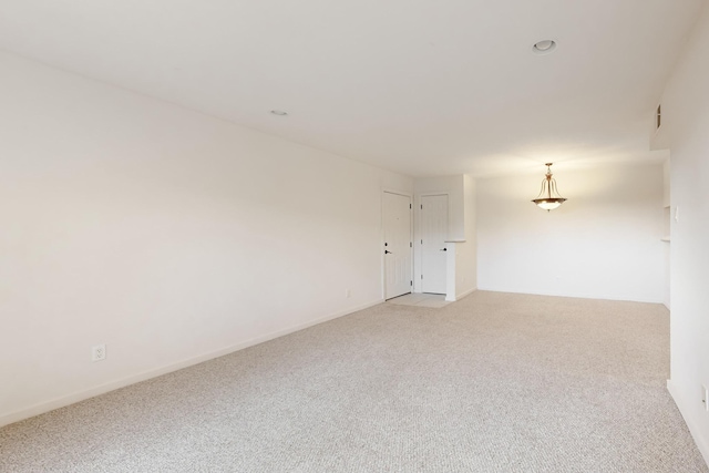 unfurnished room featuring light carpet and baseboards