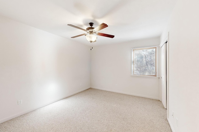 empty room featuring ceiling fan, baseboards, and light colored carpet