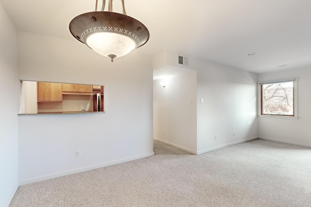 carpeted spare room featuring visible vents and baseboards